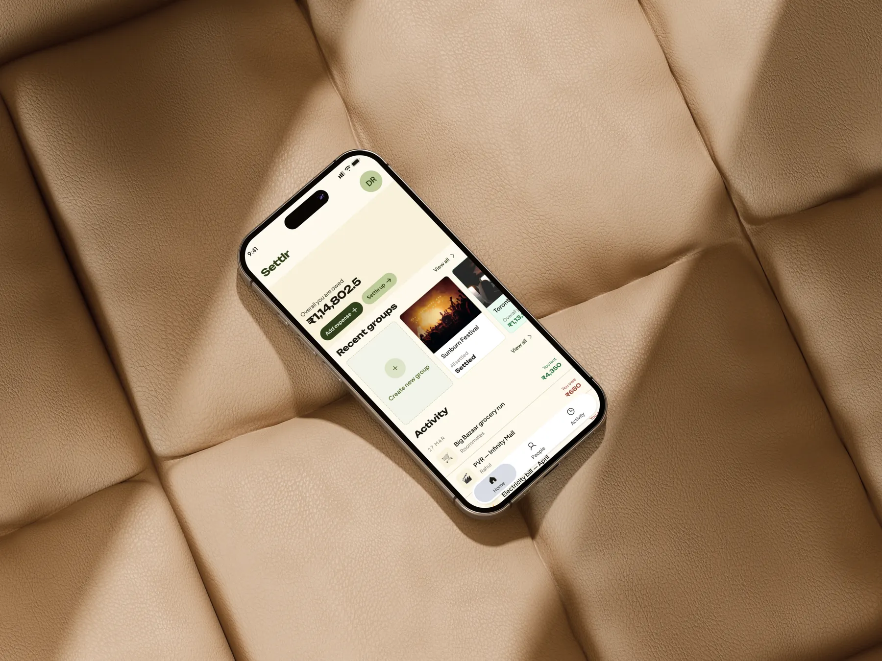 Settlr home dashboard on a phone resting on a leather sofa
